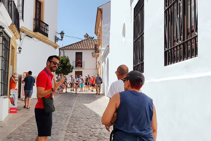 Tour guide leading a group through Ronda's charming cobblestone streets, showcasing Andalusian architecture and culture.