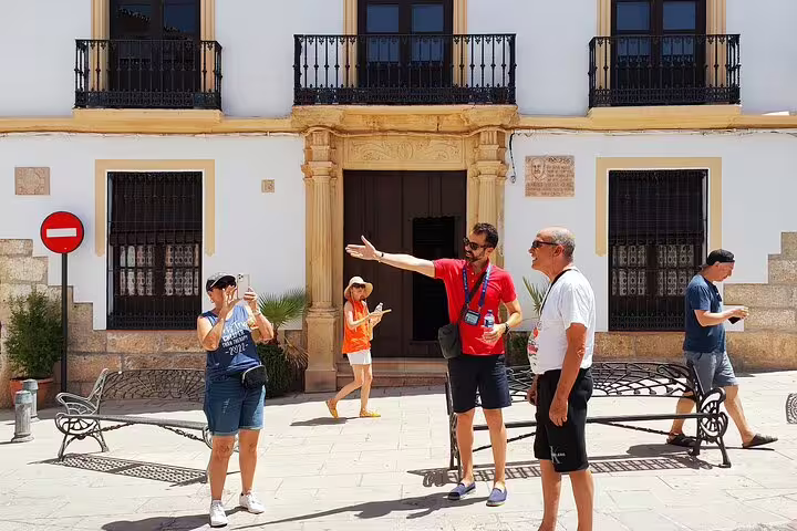 Guide gestures while explaining historical sites in Ronda's charming plaza during a private walking tour.