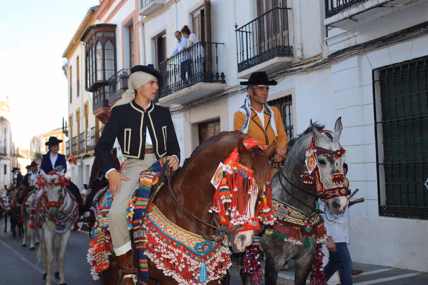 Riders in period attire parade with decorated horses at Ronda Romantica festival.