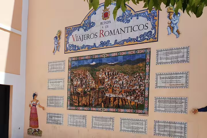 Colorful mural in Ronda depicting 'Viajeros Románticos' with detailed city illustrations and historical plaques.