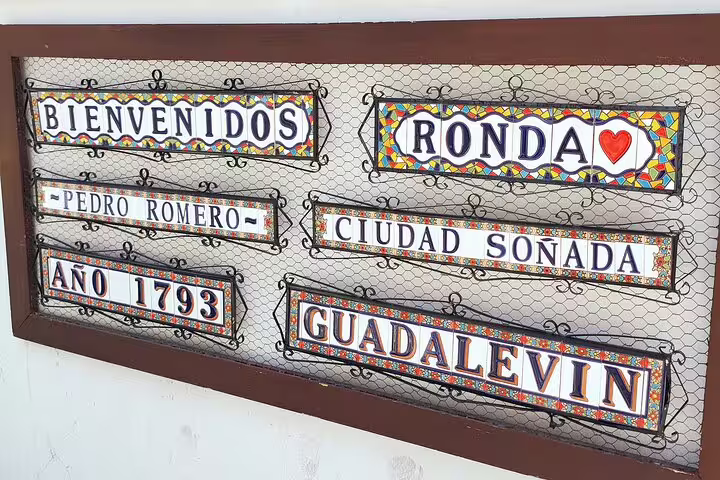 Colorful welcome sign for Ronda, featuring historic references and charming tiled designs, invites tourists.
