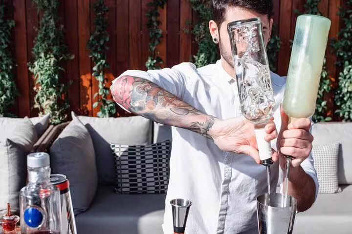Bartender with tattoos skillfully mixing cocktails at a stylish rooftop bar in Madrid, perfect for a vibrant nightlife experience.