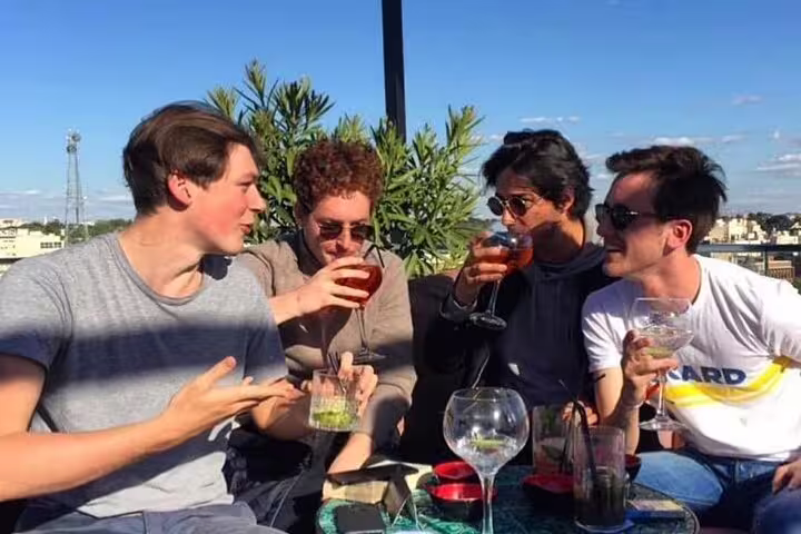 Group of friends enjoying cocktails on a sunny rooftop bar in Madrid, highlighting vibrant nightlife and scenic views.