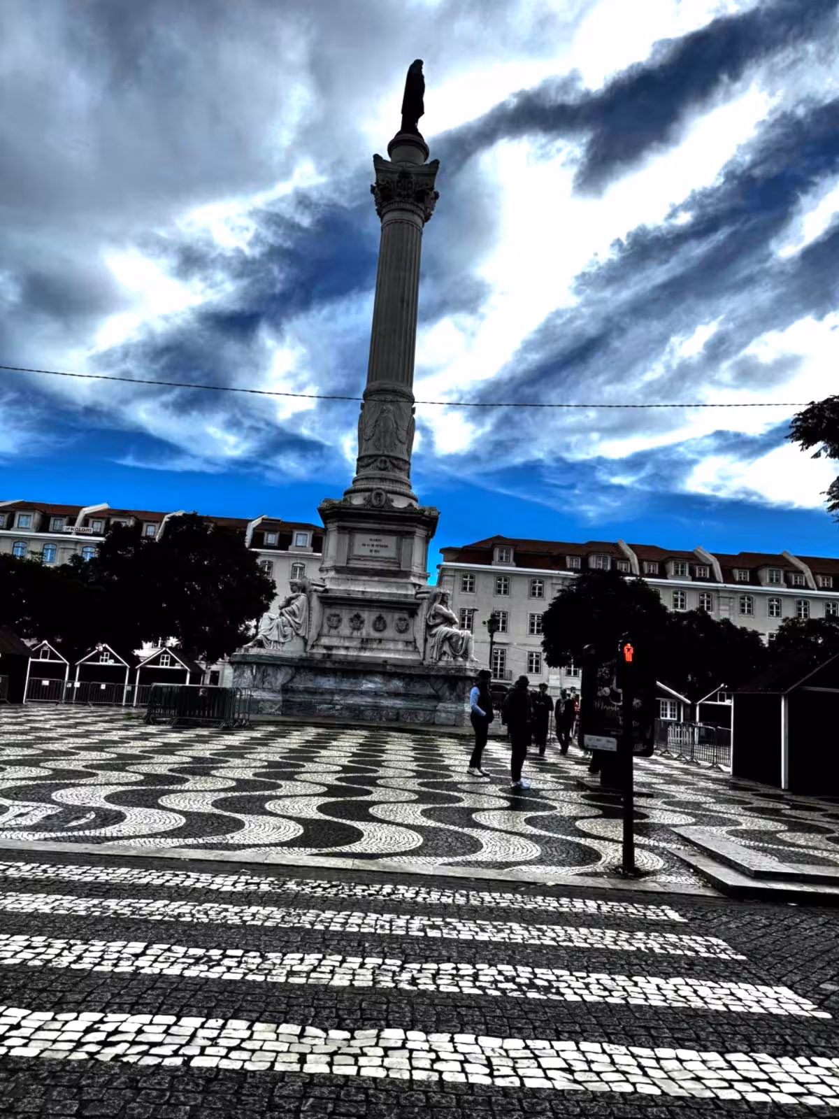 Rossio Square wave-pattern pavement and Dom Pedro IV column in Lisbon, stop on an audio guided City Quest scavenger hunt