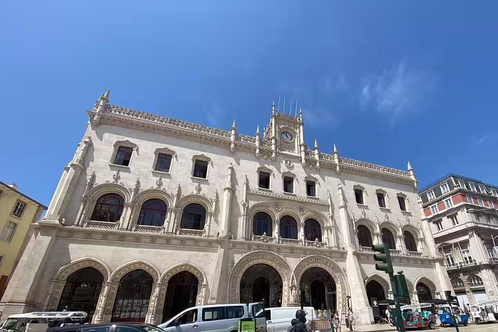 Stunning facade of Rossio Train Station in Lisbon, showcasing intricate architecture under a bright blue sky.