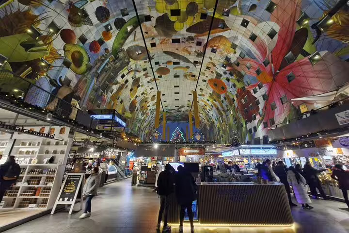 Inside Rotterdam Markthal on a walking tour, vibrant ceiling art, food stalls and local hidden gems experience
