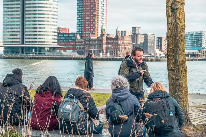 Dutch local guide briefing group by the Maas River with Rotterdam skyline, highlights and hidden gems walk