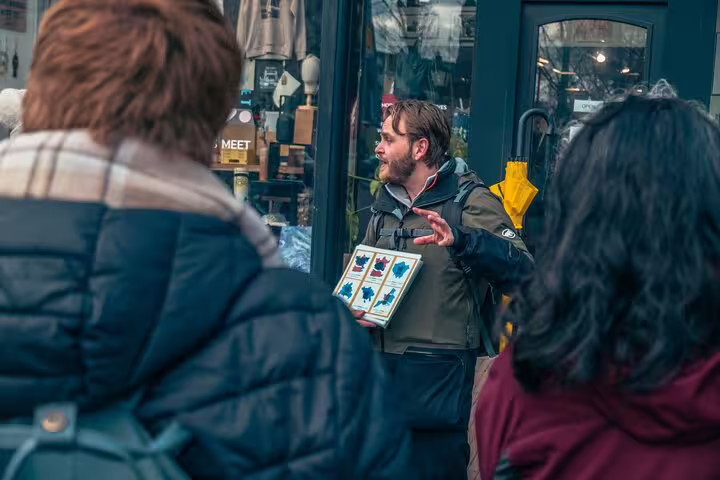 Dutch local guide explains Rotterdam hidden gems to small group outside shop, highlights walking tour experience