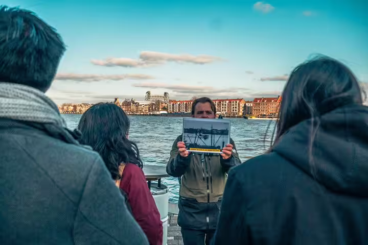 Dutch local guide shows historic photo at Rotterdam waterfront during highlights and hidden gems walking tour