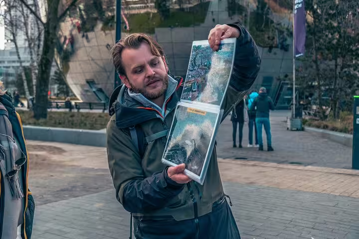 Dutch local guide shows historic photos during Rotterdam highlights and hidden gems walking tour downtown