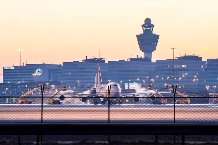 Aircraft at Schiphol Airport at sunset with terminal and control tower, for roundtrip transfer Schiphol to Amsterdam