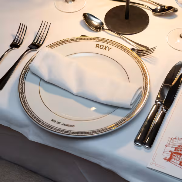 Elegant table setting at Roxy Copacabana with fine dining cutlery and a personalized dinner plate.