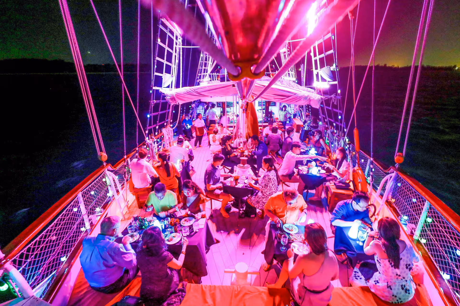 Diners savoring a buffet dinner on the illuminated deck of the Royal Albatross during a City Lights Cruise.