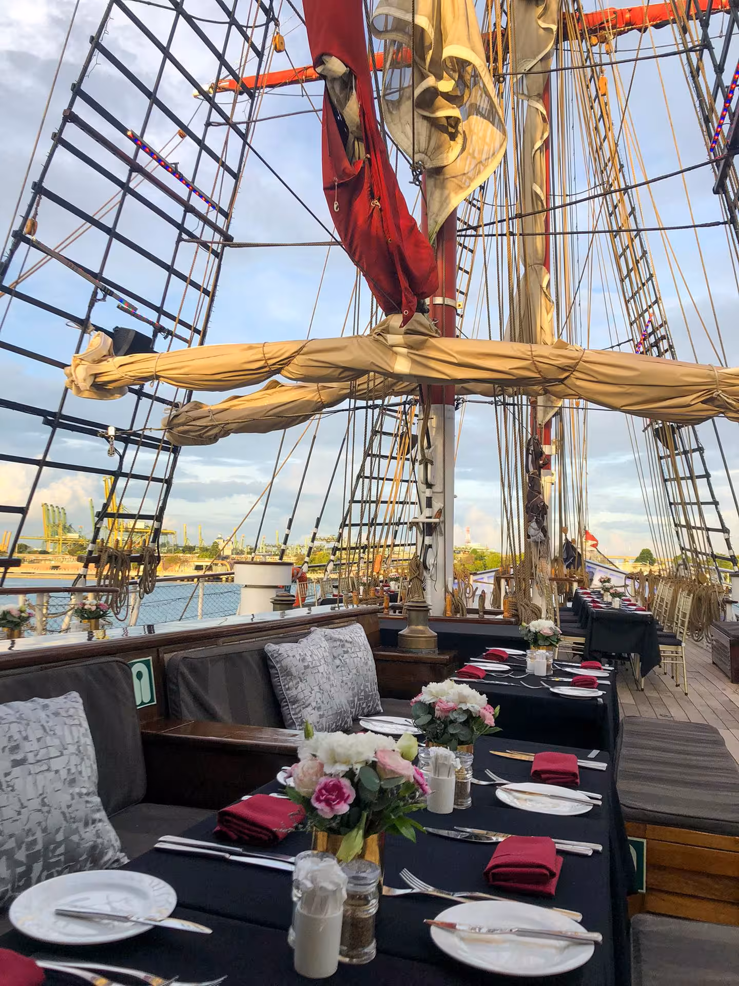 Elegant dining setup on Royal Albatross with floral arrangements and ocean view during sunset dinner cruise.