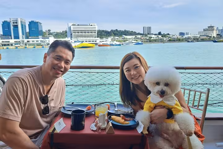 Couple with fluffy dog dining on the Royal Albatross, enjoying the sunset cruise with waterfront views.
