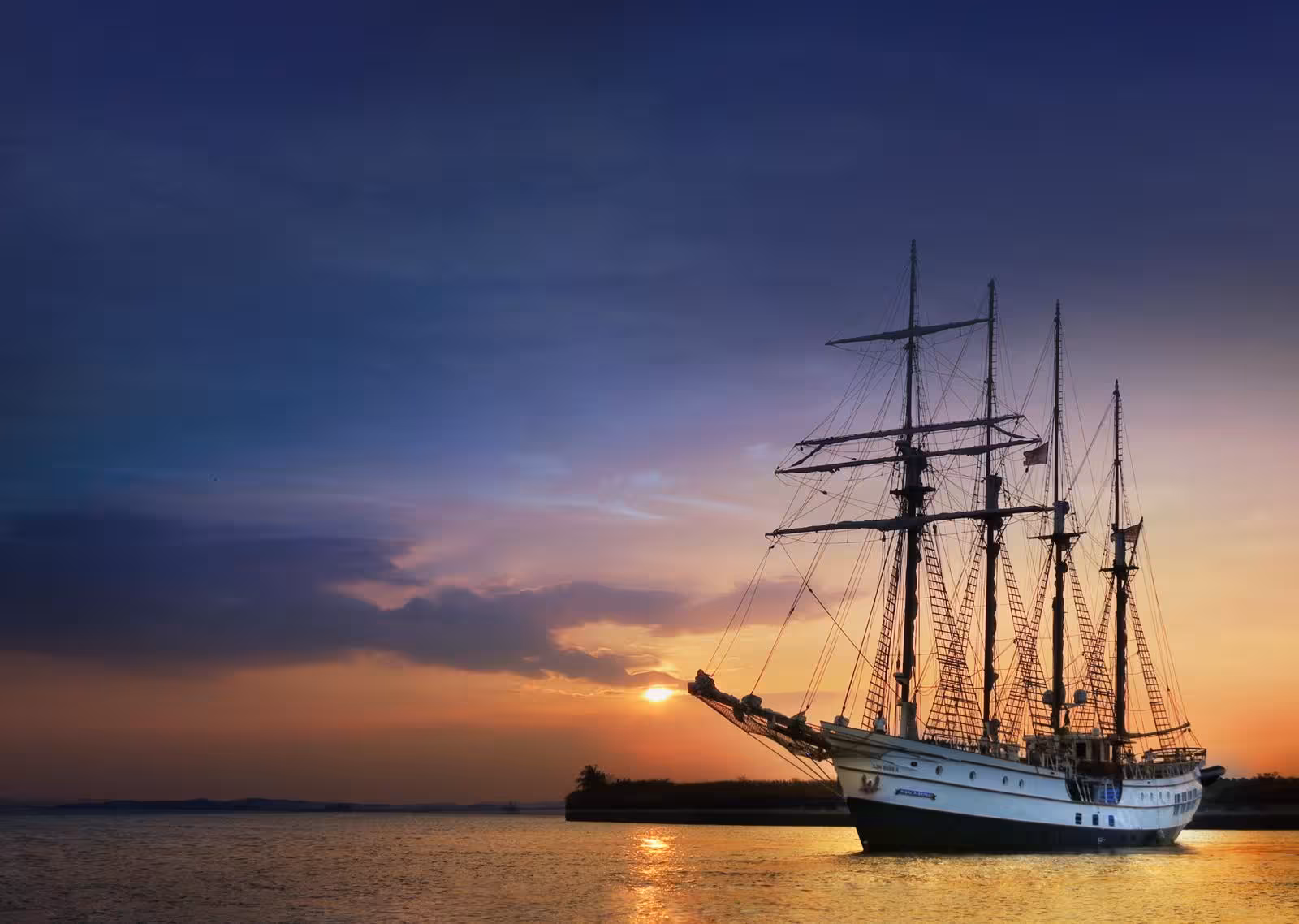 Elegant tall ship silhouetted against a vibrant sunset sky over tranquil waters.