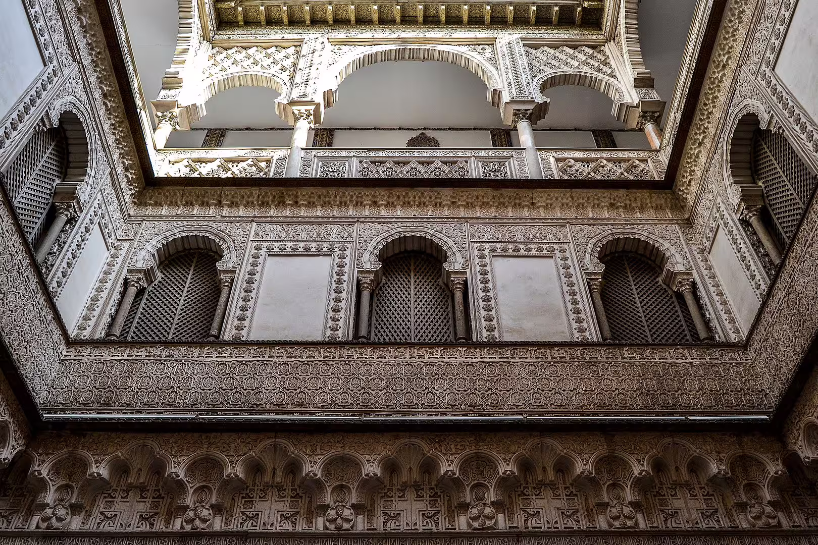 Intricate Moorish arches and detailed carvings adorn the Royal Alcazar of Seville, showcasing its architectural splendor.