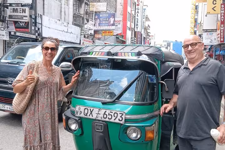 Tourists beside a green tuk tuk on a busy Colombo street for an all-inclusive Royal City Tuk Tuk tour