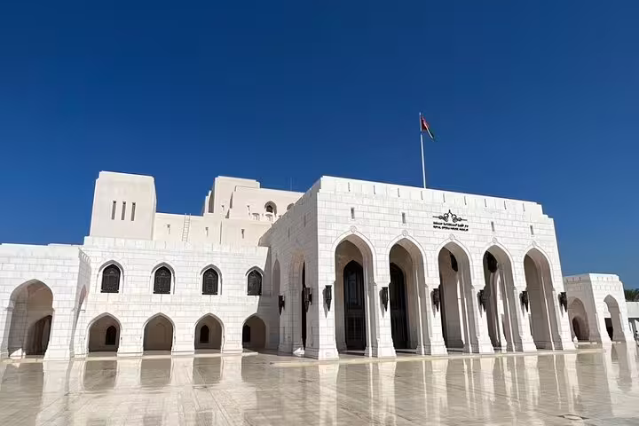 Stunning exterior of Oman's Royal Opera House with white arches and clear blue skies, ideal for an afternoon Muscat tour.