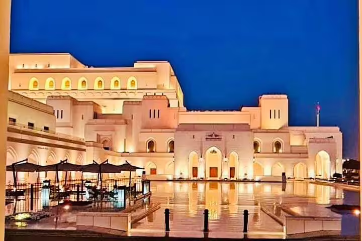 Illuminated Royal Opera House Muscat at dusk, a stunning architectural landmark featured in the city tour's itinerary.