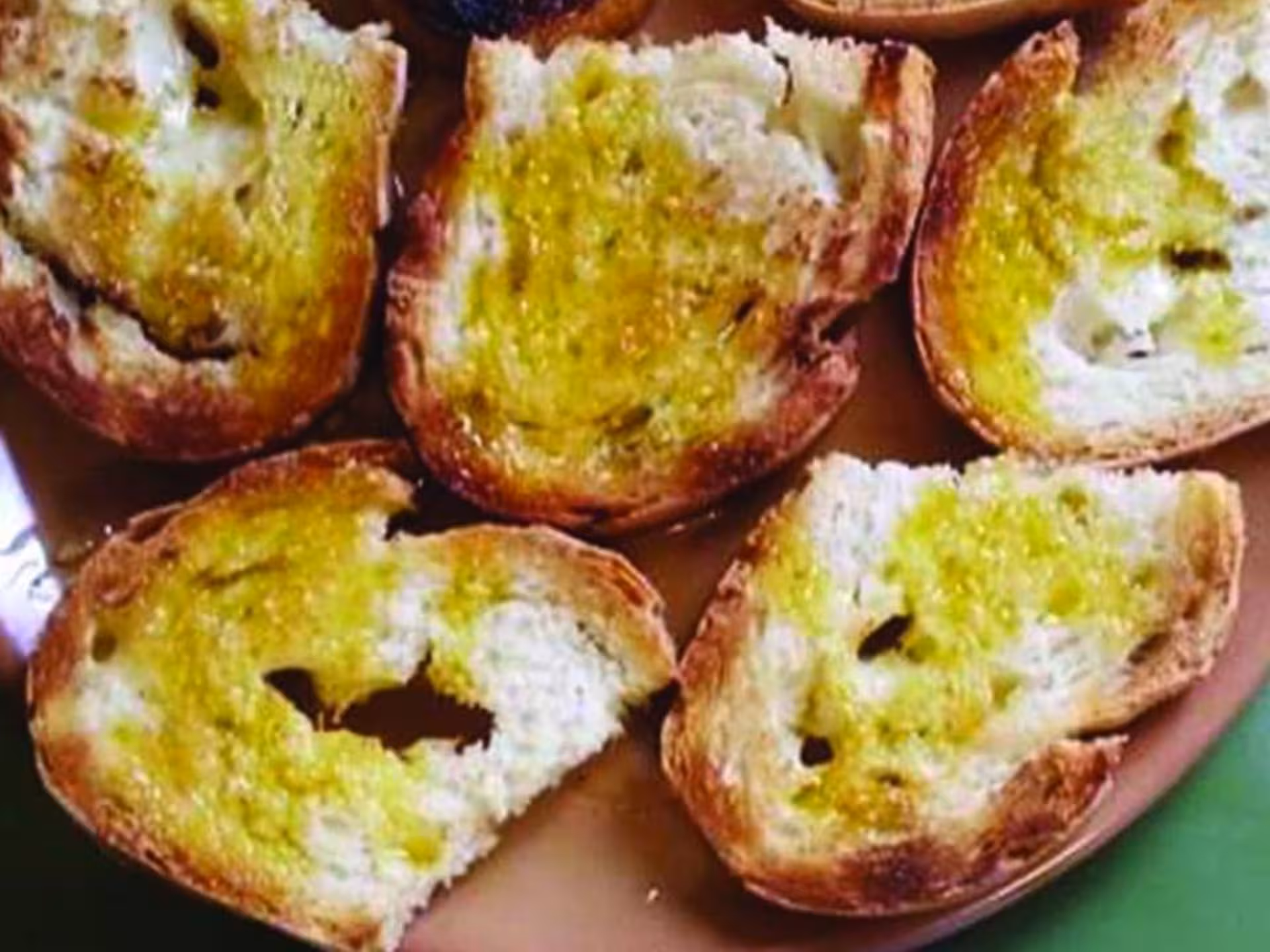 Plate of rustic bread topped with freshly pressed olive oil in Chianciano olive mill tour.