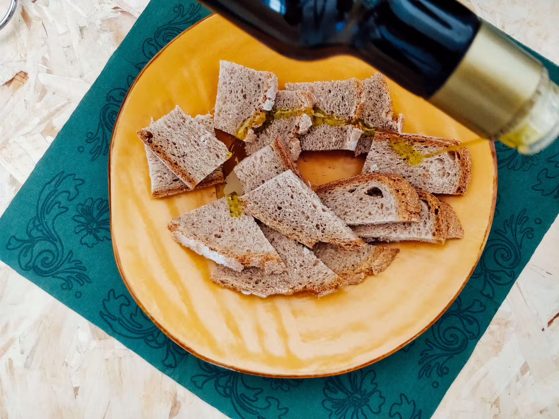 Pane rustico a fette con olio extravergine versato, degustazione all’azienda agricola Garra