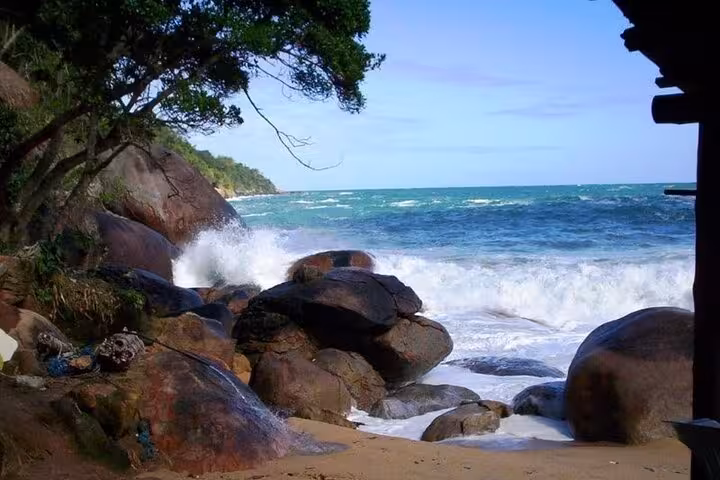 Scenic view of waves crashing against rocky shore near Saco Bravo Waterfall, a key attraction on Paraty Tours adventure.
