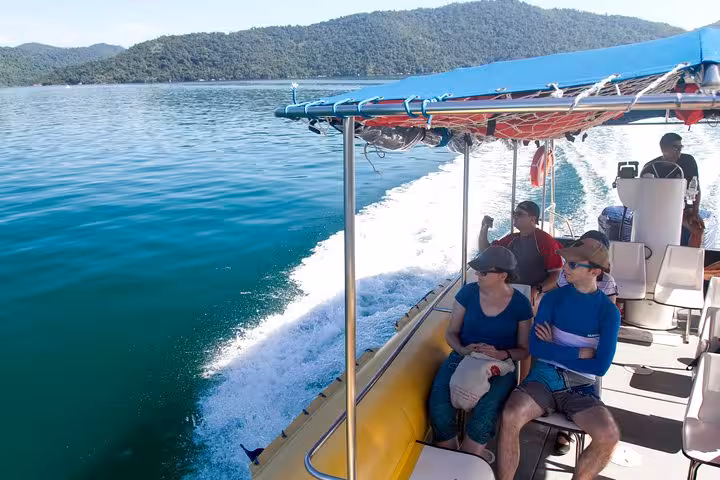 Tourists enjoy a scenic boat ride through the tranquil waters of Saco Mamanguá Fjord on a sunny day.