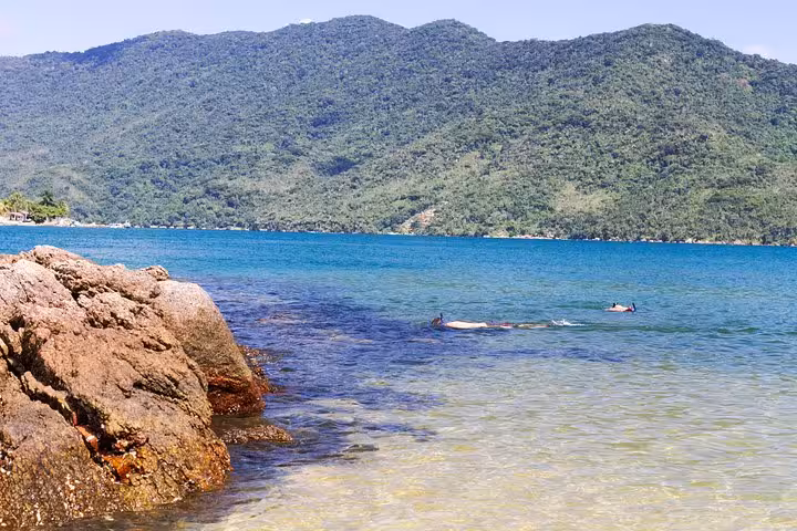 Crystal-clear waters and rocky shoreline at Saco Mamanguá Fjord, ideal for snorkeling and nature exploration.