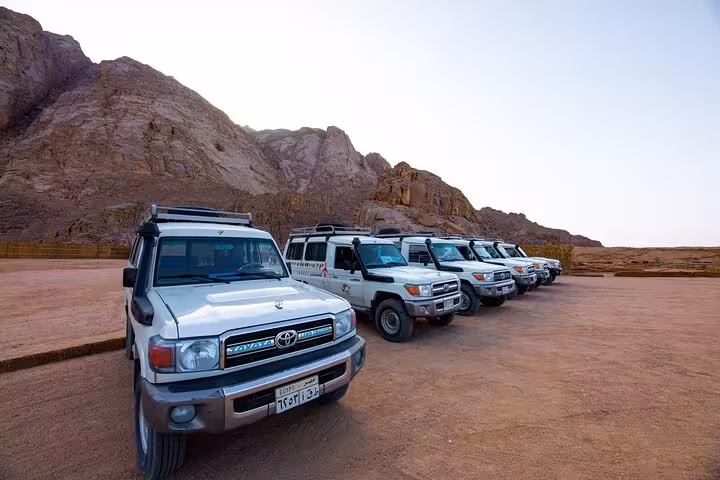 4x4 safari jeeps lined up by rocky desert mountains for Viva Safari transfer to quad, dinner and show