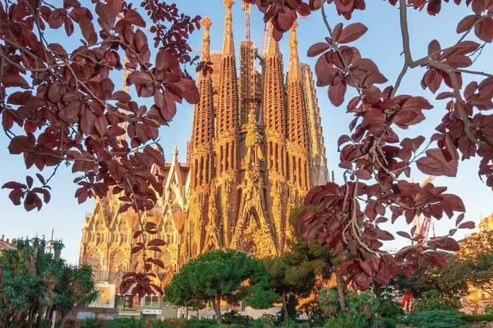 Sagrada Familia framed by autumn leaves, a highlight of the Semi-Private Barcelona Tour with Gothic and Park Guell visits.