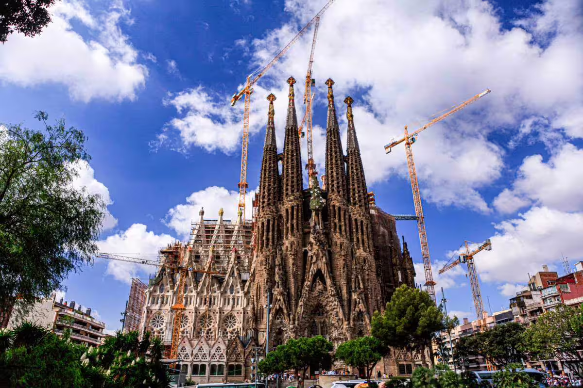 Sagrada Familia's majestic exterior with cranes under a blue sky, highlighting the ongoing construction during skip-the-line tour.