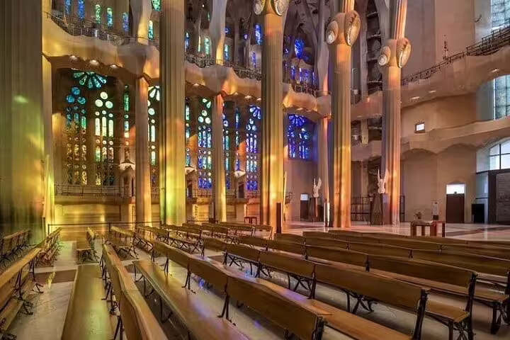 Sunlit interior of Sagrada Familia with colorful stained-glass windows and empty pews on a guided insider tour in Barcelona