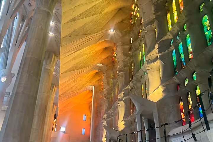 Sagrada Familia interior with warm orange and yellow stained glass illuminating the detailed architectural design.
