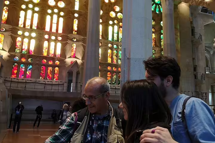 Visitors admire vibrant stained glass windows inside Sagrada Familia during a private food and drink tasting tour in Barcelona.