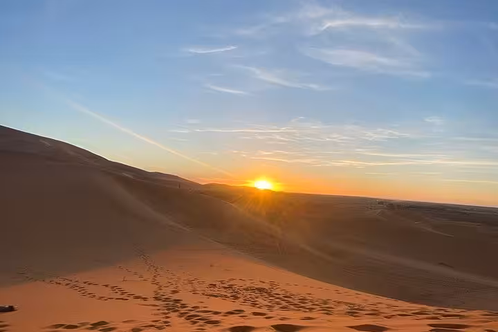 Sunset over the Sahara Desert dunes during a luxury Morocco tour from Fes, highlighting the serene desert landscape.