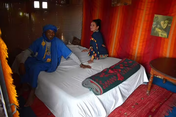 Guests relaxing in a Sahara desert tent bedroom during a private 2-day Marrakech to Zagora desert tour