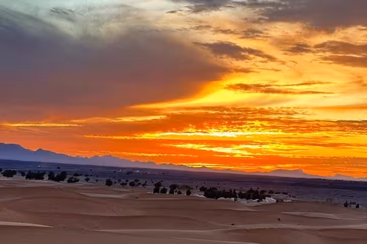 Vibrant sunset over Sahara Desert with distant dunes, captured during the 3-day Marrakech to Fes desert tour.