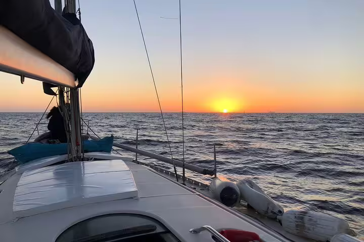 Sailboat cruising during a breathtaking Douro River sunset tour, capturing serene sea views as the sun dips below the horizon.