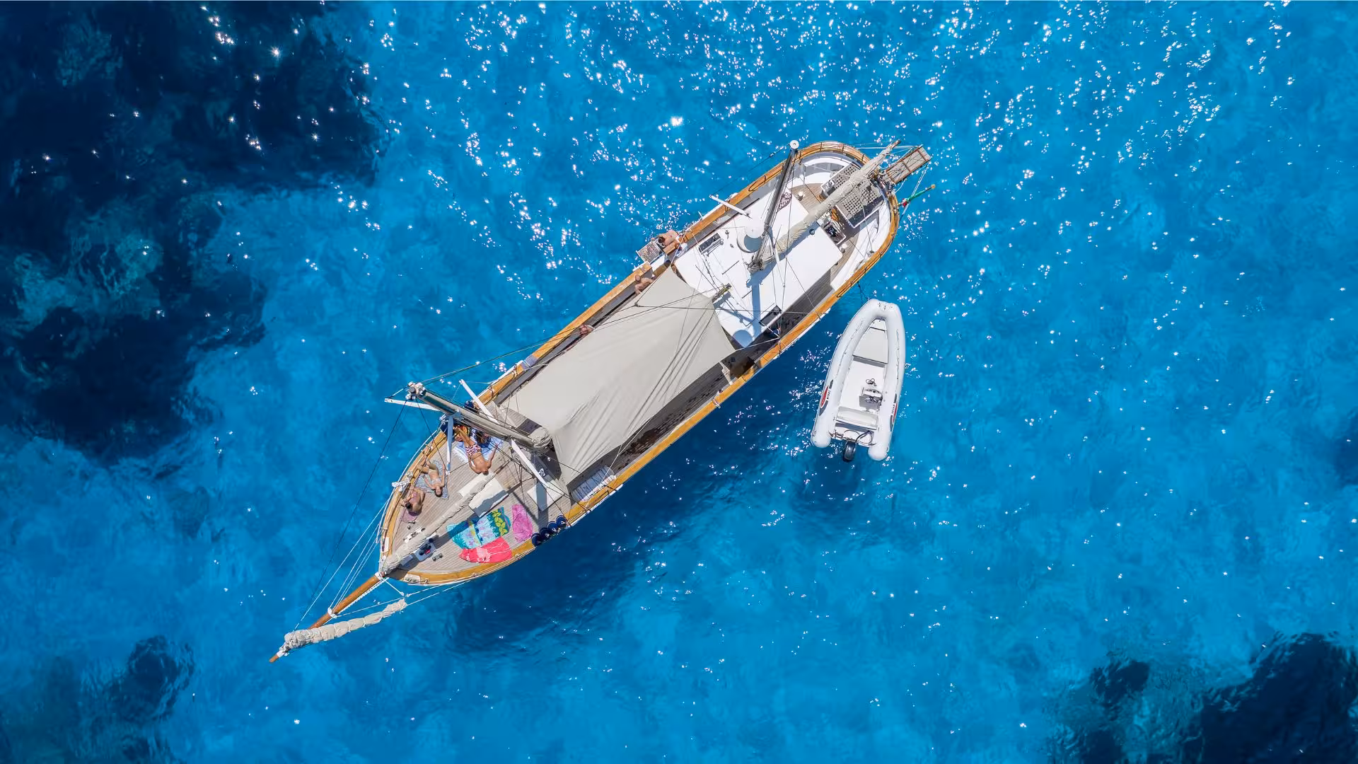 Aerial view of a sailboat and dinghy floating on the crystal-clear waters of the Gulf of Orosei near Cala Gonone.