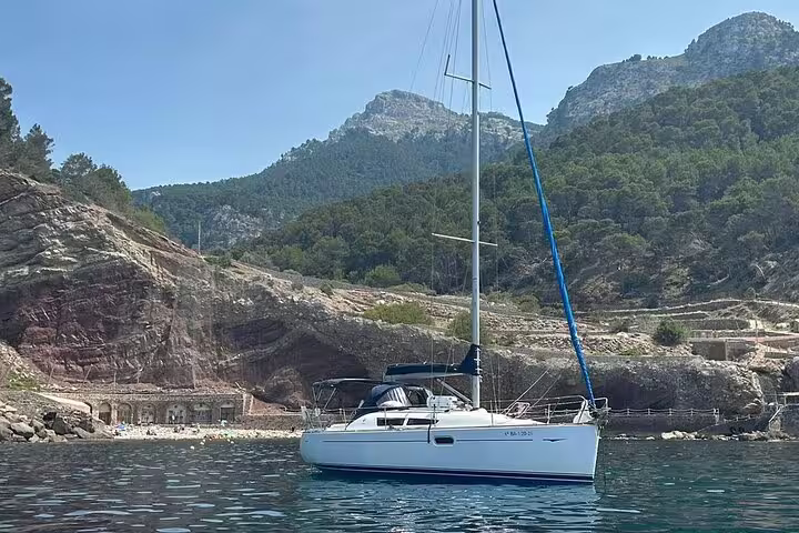 Sailboat anchored in crystal-clear waters with lush green hills in the background on a scenic Ibiza and Formentera day trip.