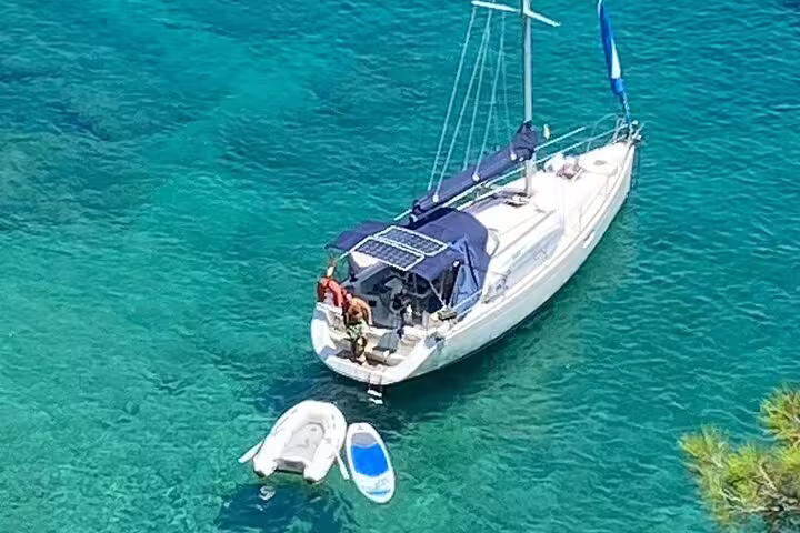 A sailboat anchored in crystal-clear turquoise waters during a private day trip to Ibiza and Formentera, offering a serene escape.