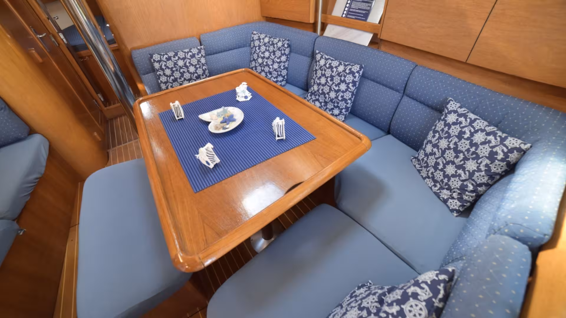 Cozy sailboat interior with blue cushioned seating, perfect for relaxing on a La Maddalena Archipelago tour.