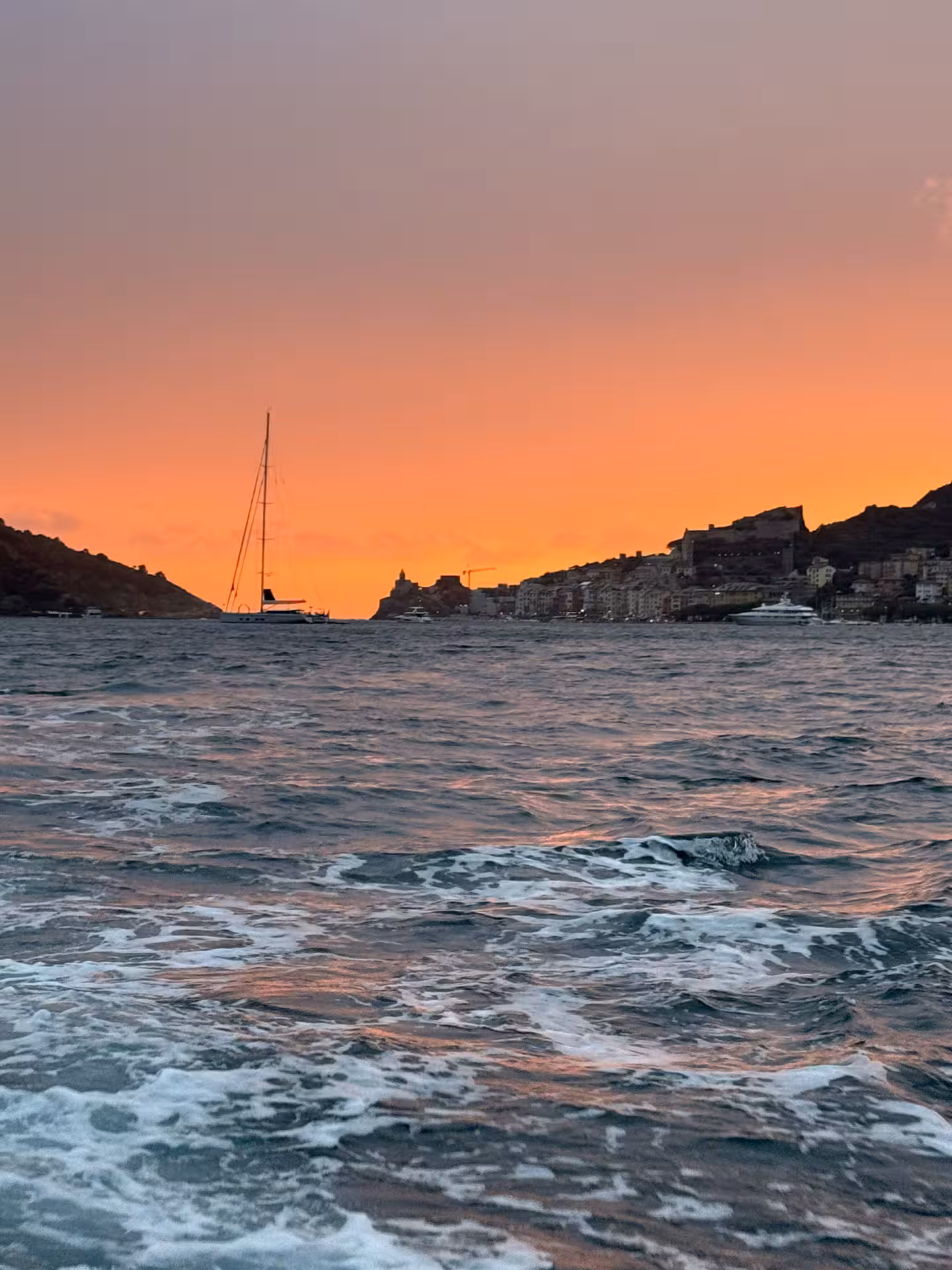 Sailboat silhouetted against a vibrant sunset in Golfo Dei Poeti, La Spezia, ideal for a serene boat tour.