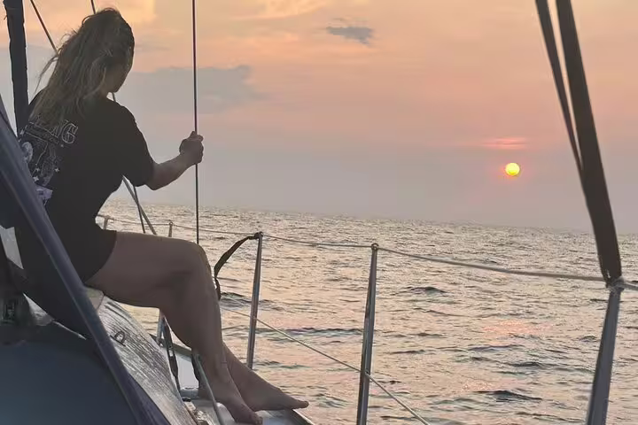 Person enjoying a serene sunset on a sailboat during a full day sailing experience around Ibiza and Formentera.
