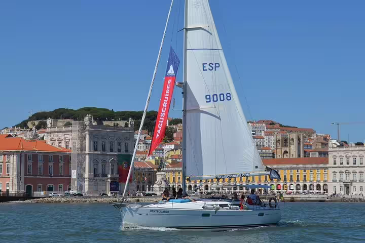 Sailboat cruising on the Tagus River with Lisbon's historic architecture in the background on a sunny day.
