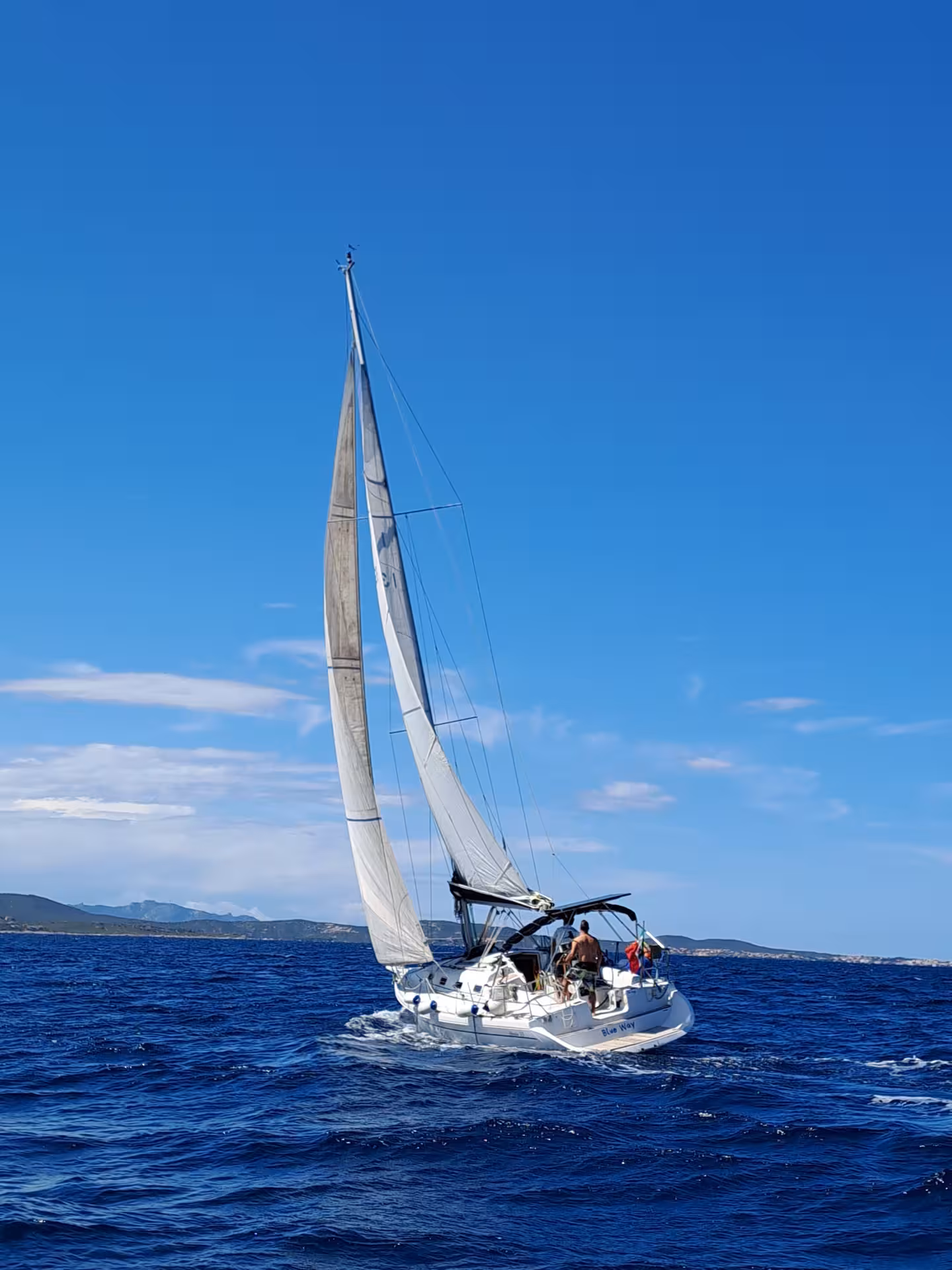 Sailboat gliding through vibrant blue seas under a clear sky on the Tavolara to Cala Moresca tour from Olbia.