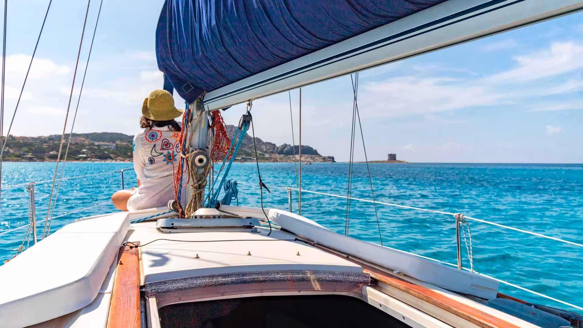 Scenic sailboat journey from Stintino to Asinara with a view of the island's coastline and azure sea.