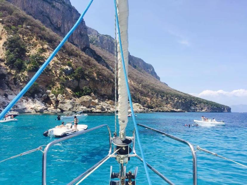 View from a sailing boat in the Gulf of Orosei, showcasing turquoise waters and rugged coastal cliffs, ideal for tours.