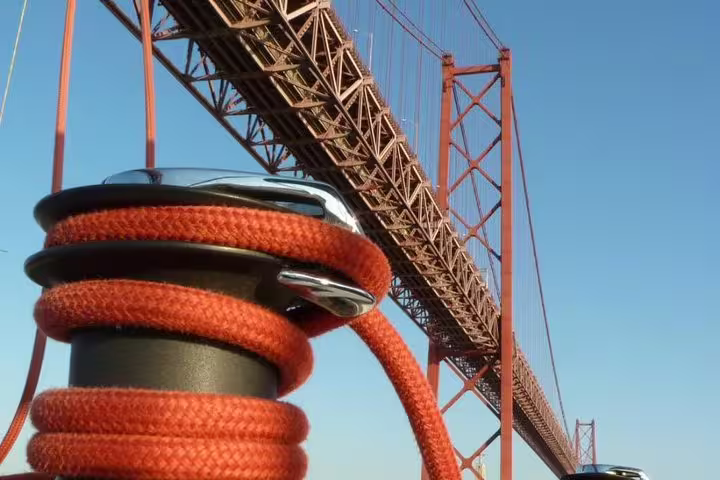 Close-up of sailing rope against the backdrop of Lisbon's 25 de Abril Bridge during a Tagus River tour.